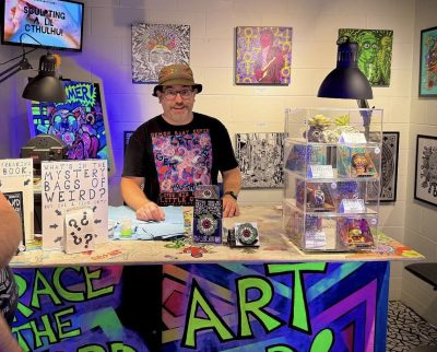 The artist Brian standing behind his art bar. 